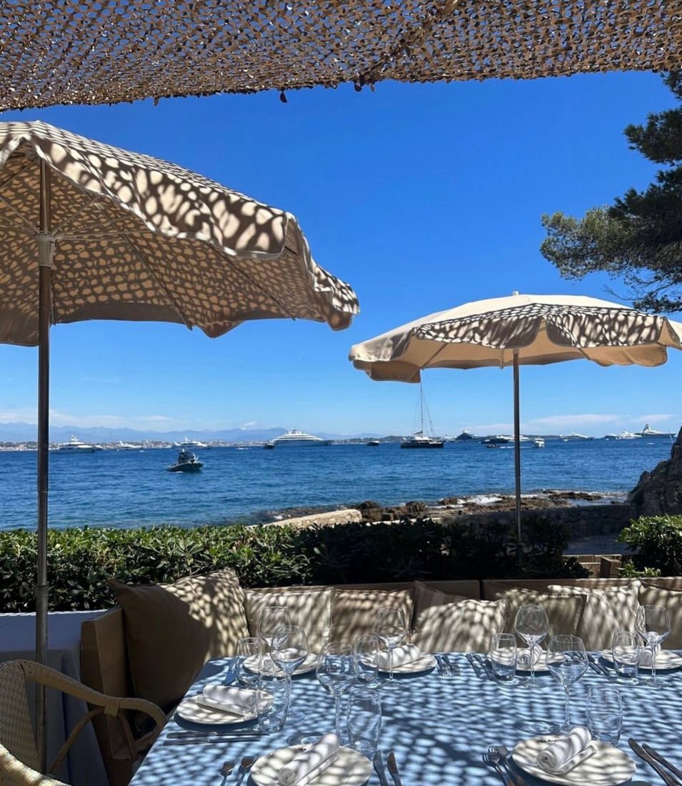 Table set for lunch under an umbrella overlooking the sea and moored yachts at La Guérite in Cannes